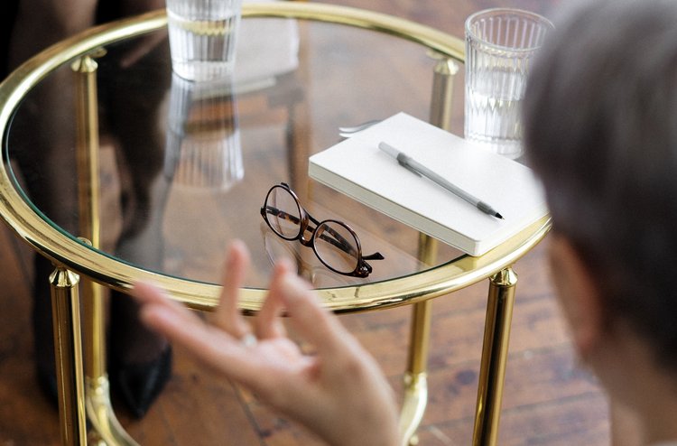 Zwei Personen sitzen sich gegenüber mit einem Tisch in der Mitte
