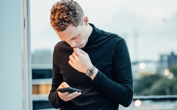 Internetsucht - Mann in schwarzem Oberteil, der auf sein Handy starrt