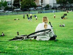 Artikel Rückenschmerzen: Frau mit Fahrrad auf einer Wiese