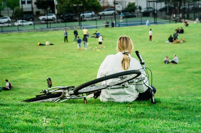 Artikel Rückenschmerzen: Frau mit Fahrrad auf einer Wiese
