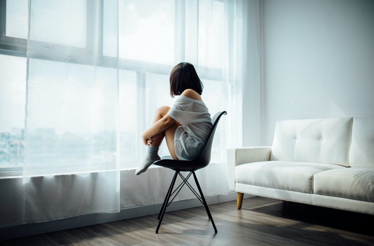 Frau sitzt traurig am Fenster