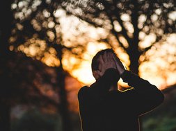 Borderline - Mann mit Händen vor dem Gesicht mit Wald im Hintergrund