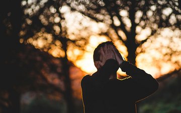 Borderline - Mann mit Händen vor dem Gesicht mit Wald im Hintergrund
