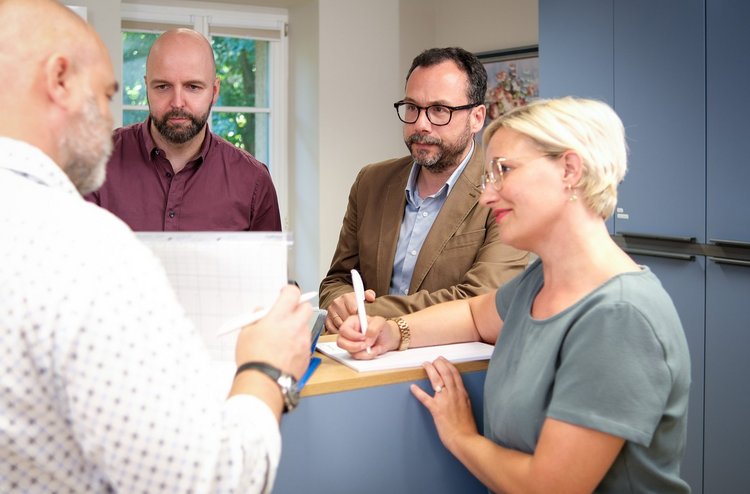 Kollegen und Kollegin stehen zusammen am Tresen und tauschen sich aus