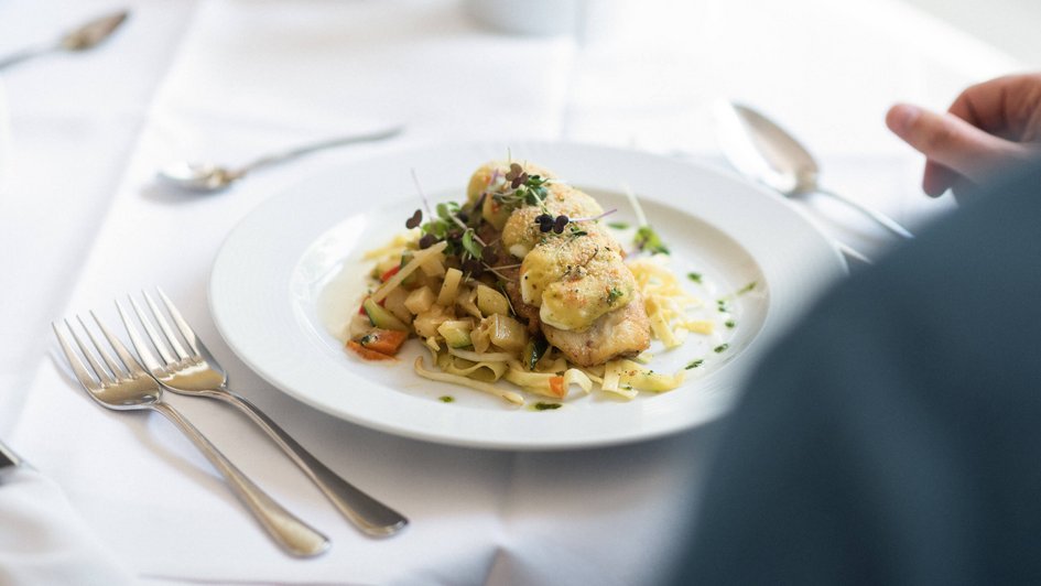 Gedeckter Tisch, auf dem ein Teller mit Essen steht.  