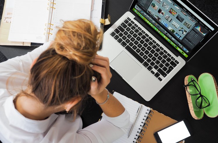 Frau sitzt gestresst am Arbeitsplatz